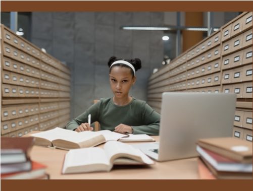 Student at desk with books and laptop