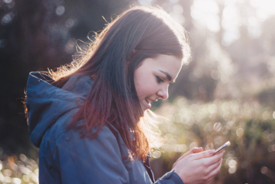 A girl smiles enthusiastically at her phone