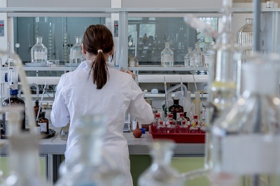 A student in a white lab coat works in a laboratory
